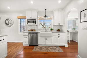 Kitchen featuring white cabinetry, stainless steel appliances, dark wood-style floors, tasteful backsplash, and pendant lighting