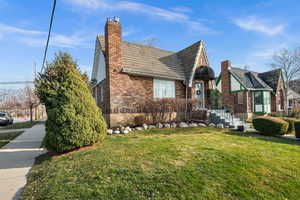View of front facade featuring a front lawn, brick siding, and a chimney