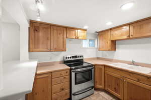 Kitchen with stainless steel range with electric cooktop, light countertops, and light tile patterned floors