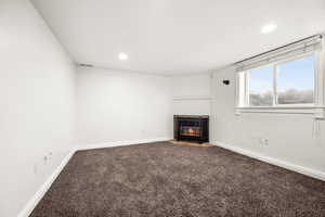 Unfurnished living room featuring a fireplace with flush hearth, carpet, and recessed lighting
