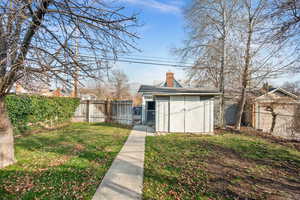 Back of house with a fenced backyard, a chimney, an outbuilding, and a gate