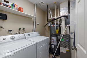 Laundry room with gas water heater, heating unit, and washer and clothes dryer