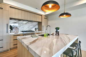 Kitchen featuring light stone counters, modern cabinets, and a kitchen island with sink