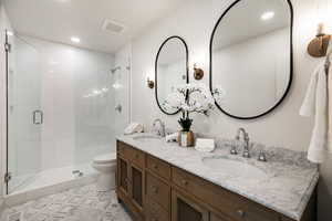Full bathroom with double vanity, a stall shower, and recessed lighting
