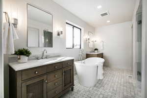 Full bath with two vanities, a freestanding bath, recessed lighting, and light flooring