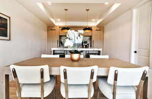 Dining area featuring recessed lighting, a raised ceiling, and light wood-type flooring