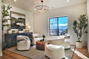 Sitting room with suspended lighting, wood finished floors, and a mountain view