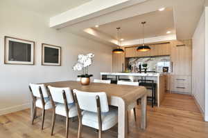 Dining room with light wood finished floors, recessed lighting, and a tray ceiling