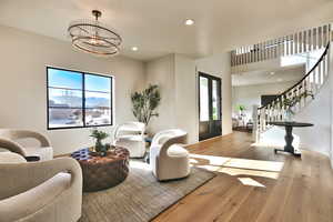 Foyer with light wood-style floors, hanging lights, and french doors