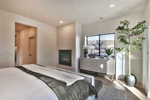Bedroom featuring wood finished floors, recessed lighting, and a glass covered fireplace
