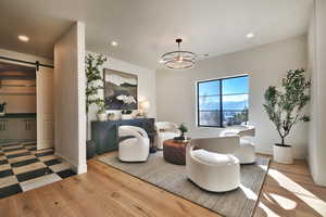Sitting room with a barn door, light wood-style flooring, and suspended lighting