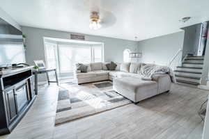 Living area with a textured ceiling, wood tiled floors, stairway, and a ceiling fan