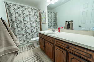 Full bath with a shower with shower curtain, vanity, and light tile patterned flooring