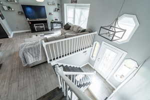 Living room with wood tiled floors, a chandelier, stairway, and a glass covered fireplace