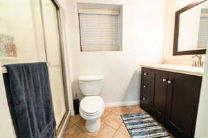 Full bathroom featuring vanity, a shower stall, and light tile patterned flooring