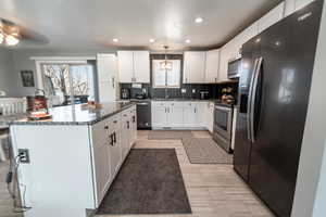 Kitchen featuring stainless steel appliances, white cabinetry, dark stone countertops, a center island, and recessed lighting