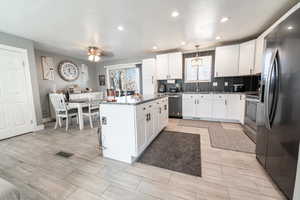Kitchen featuring stainless steel appliances, white cabinets, a center island, backsplash, and recessed lighting