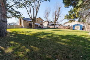 Fenced backyard featuring a storage unit