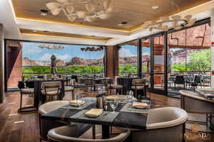 Dining area with a raised ceiling, wooden ceiling, dark wood-style floors, expansive windows, and a chandelier
