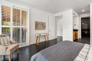 Bedroom featuring access to exterior, dark wood-style flooring, ensuite bath, and recessed lighting
