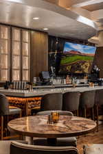 Community bar area with modern cabinets, dark brown cabinetry, glass insert cabinets, and recessed lighting
