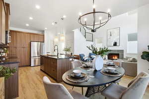 Dining room with a tile fireplace, recessed lighting, light wood finished floors, and a chandelier