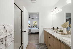 Full bath with ensuite bathroom, double vanity, a shower stall, and dark tile patterned floors
