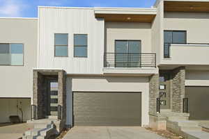 Contemporary house featuring stone siding, stucco siding, an attached garage, and a balcony