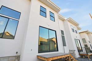 View of side of home featuring stucco siding and a wooden deck