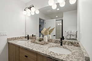 Full bathroom with double vanity and a stall shower