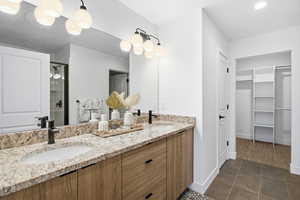 Bathroom featuring a walk in closet, double vanity, a shower stall, dark tile patterned flooring, and recessed lighting