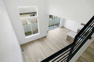 Stairway with plenty of natural light, wood finished floors, and a towering ceiling