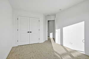 Unfurnished bedroom with light carpet and a closet