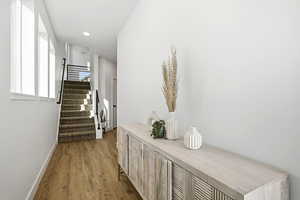 Hallway with dark wood finished floors, stairs, and recessed lighting