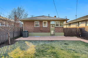 Rear view of house with a patio, brick siding, a fenced backyard, a chimney, and a shingled roof
