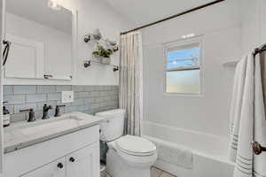 Full bathroom featuring shower / bath combo, vanity, and tile walls