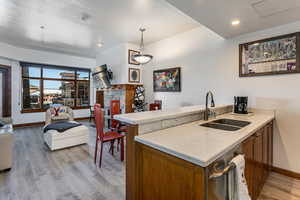 Kitchen featuring a peninsula, light countertops, pendant lighting, light wood finished floors, and recessed lighting