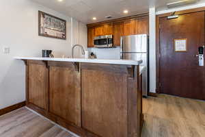Kitchen with brown cabinets, light countertops, a breakfast bar, a peninsula, and stainless steel appliances