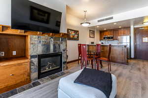 Living room with wood finished floors, a stone fireplace, and recessed lighting