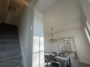 Stairway with wood finished floors and a chandelier