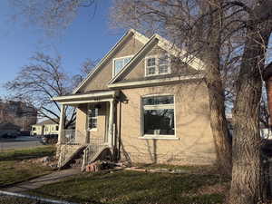 View of front of house featuring covered porch, brick siding, and a front yard