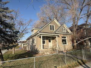 View of front of home with a fenced front yard, a porch, and brick siding