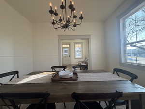 Dining area with a wainscoted wall and a chandelier
