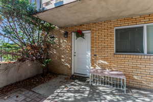 View of exterior entry featuring brick siding and a patio area