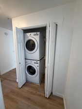 Laundry area featuring stacked washing machine and dryer and light wood-type flooring