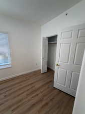 Unfurnished bedroom featuring dark wood-type flooring and a closet