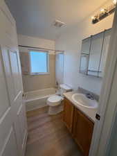 Full bathroom with vanity, shower / tub combination, light wood-type flooring, and a textured ceiling