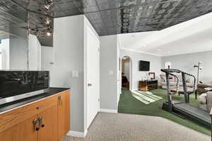 Bar with dark countertops, arched walkways, stainless steel microwave, brown cabinets, and recessed lighting