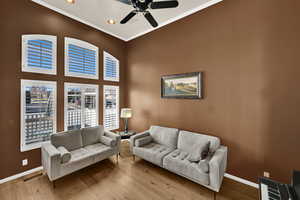 Living area with crown molding, wood-type flooring, a ceiling fan, recessed lighting, and a high ceiling