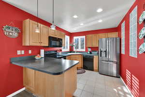 Kitchen featuring black appliances, dark countertops, decorative light fixtures, a peninsula, and a textured ceiling
